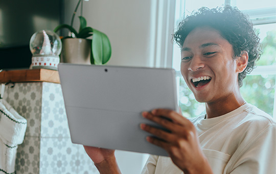 Student laughing holding a screen